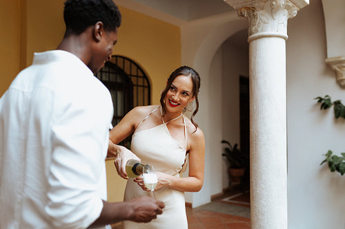 Happy young couple pouring sparkling wine into a glass