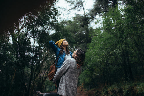 Young smiling couple enjoying rain in the forest