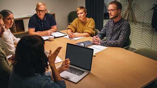 Colleagues listening to female executive in board meeting
