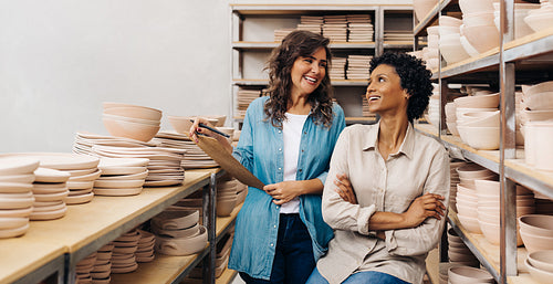 Two ceramic shop owners smiling at each other in their store