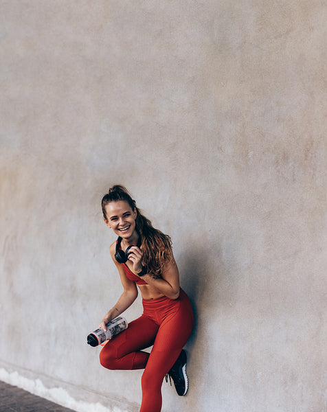Woman in sportswear standing by a wall