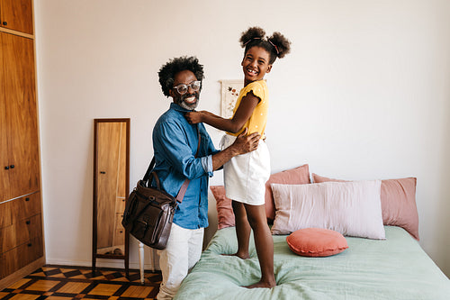 Single father getting his shirt fixed by his daughter before work