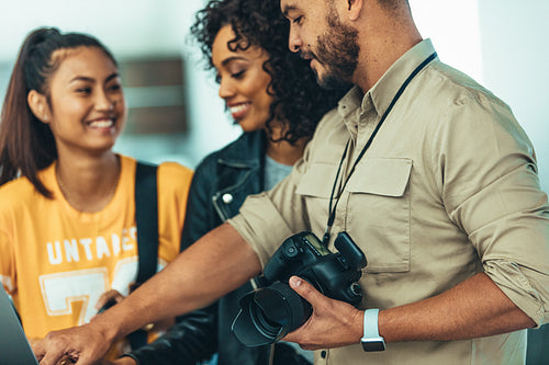 Photographer showing the photos to his team on laptop