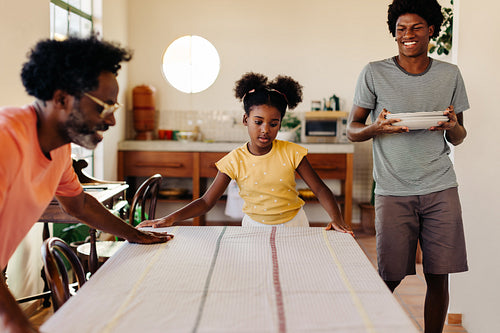 Family helping each other set the table for a breakfast meal at home