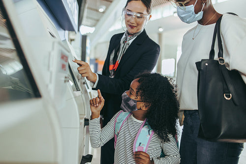 Attendant helping a family doing the self check-in at the airpor