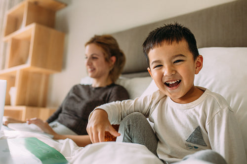 Cute little boy on bed with mother at back