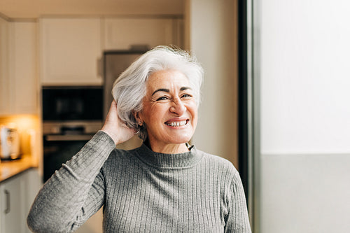 Cheerful senior woman smiling at the camera at home