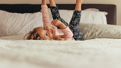 Little girl playing on bed