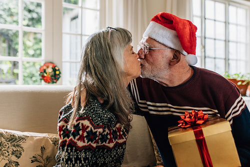 Happy senior couple kissing each other celebrating christmas