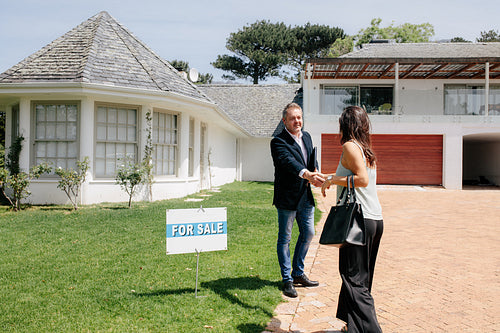 Realtor greeting client outside new house for sale