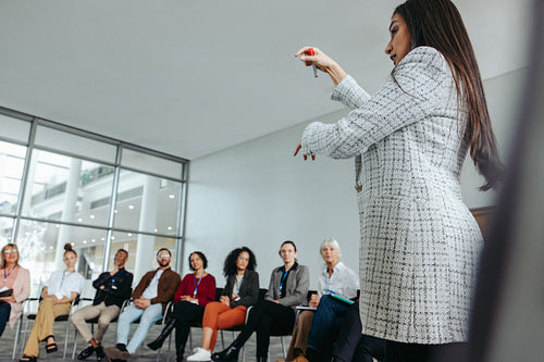 Female professional presenting at office event with audience in modern conference room