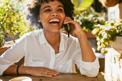 Woman smiling and talking on phone at a cafe