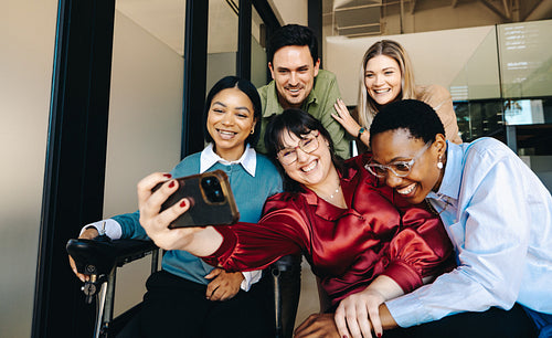 Group of diverse coworkers smiling while taking a selfie in their office space