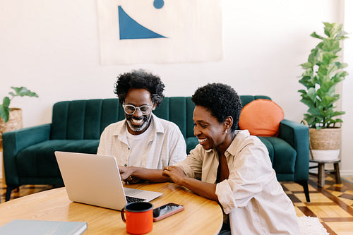 Happy mature couple watching a movie on a laptop in their living room