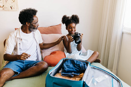Father and daughter packing a travel camera for a family vacation
