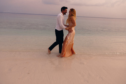 Playful couple enjoying a romantic wedding on a tropical island beach at sunset