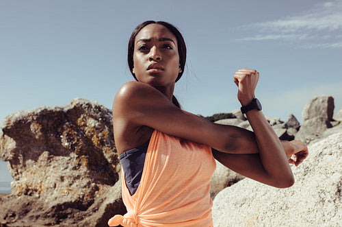 Woman stretching her arm muscle at the beach
