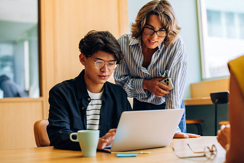 Young man and woman collaborating on a laptop at a desk