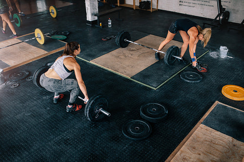Muscular women exercising with heavy weights in gym