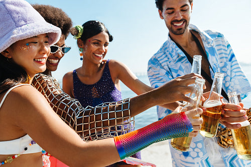 Friends raise bottles on sunny beach celebration