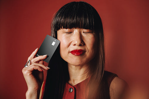 Confident woman holding black card in studio portrait for personal finance theme