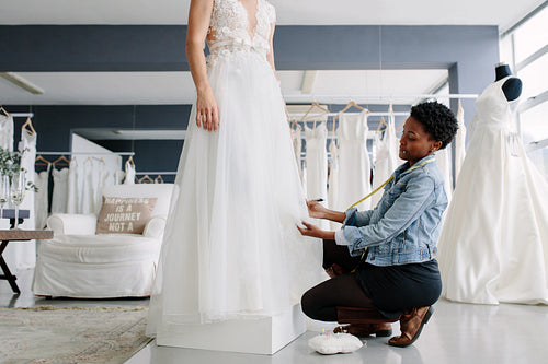 Woman making adjustment to wedding gown in designer studio