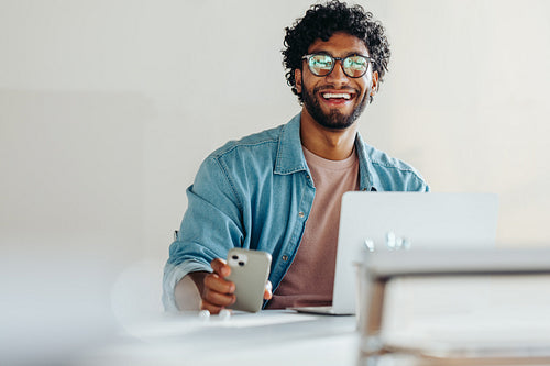 Cheerful young businessman working with tech in office