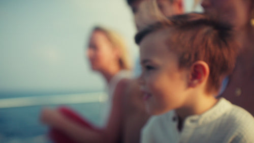 Happy family on boat during beautiful sunset cruise searching for dolphins