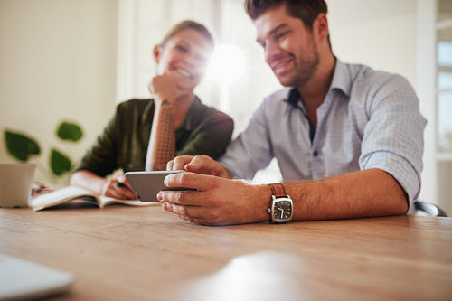Young couple at table using cellphone at home