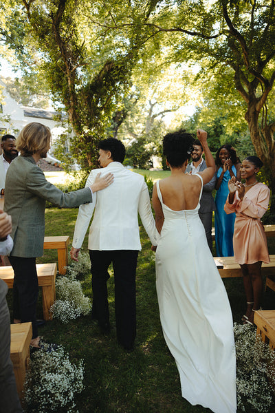 Newlywed couple walking joyfully through applauding guests at an outdoor ceremony