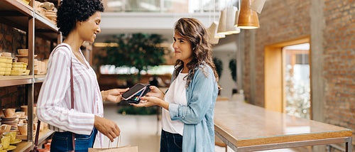 Cheerful shop owner receiving an NFC payment from a customer