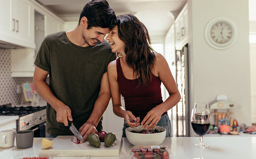 Loving couple cutting vegetables together in kitchen