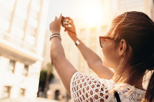 Young tourist recording selfie in a street surrounded by buildings.