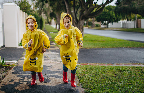 Two identical twin sisters in raincoats