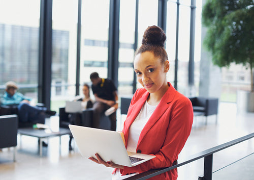 Beautiful young businesswoman with laptop in modern office