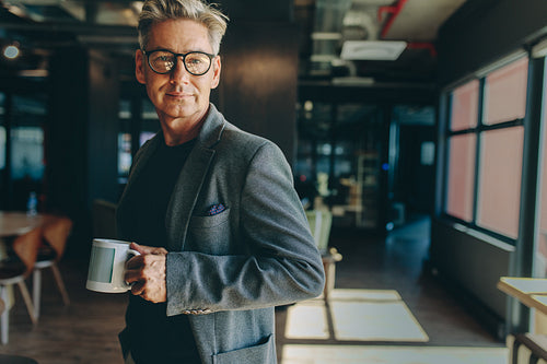 Businessman standing in office holding a coffee cup