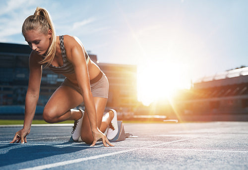 Female sprinter in track starting blocks