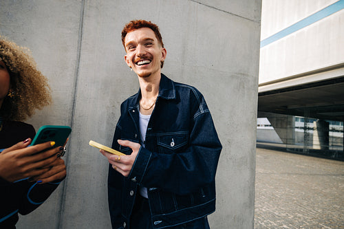 Smiling friends using smartphone in urban setting