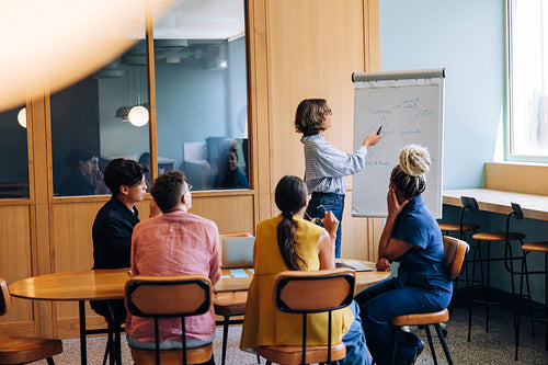 Team discussing strategy during a casual office meeting around a whiteboard