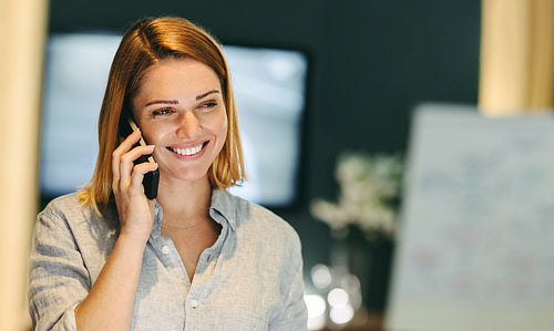 Cheerful businesswoman speaking on a phone call in an office