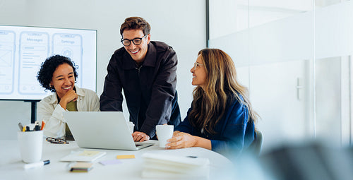 Three designers review laptop screen during team session