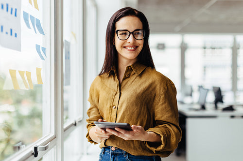 Thoughtful business woman holding a tablet in an office