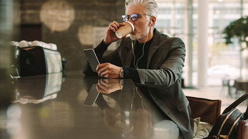 Businessman with phone drinking coffee