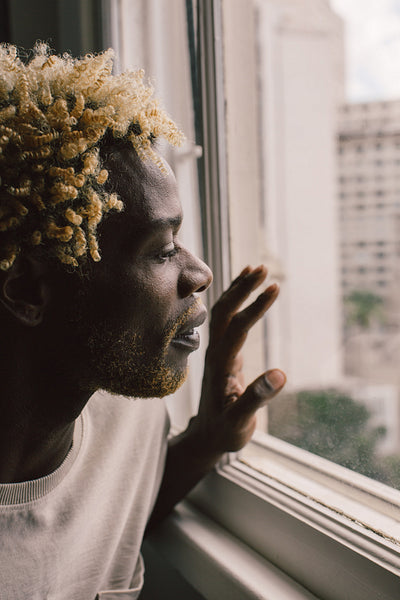 Black gay man looking outside his window