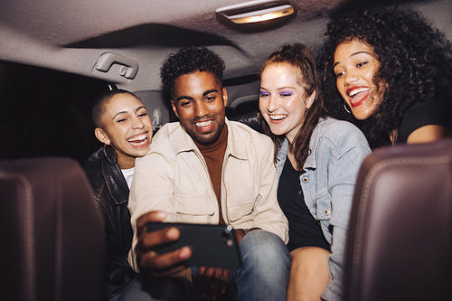 Happy friends taking a selfie together inside a car