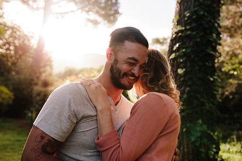 Handsome young man embracing his girlfriend in a park
