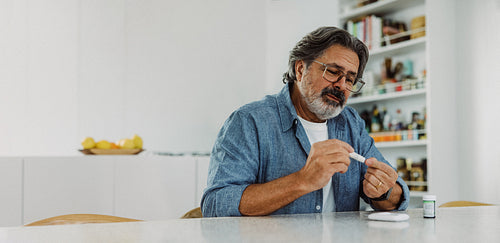 Senior man tests glucose with a lancet at home