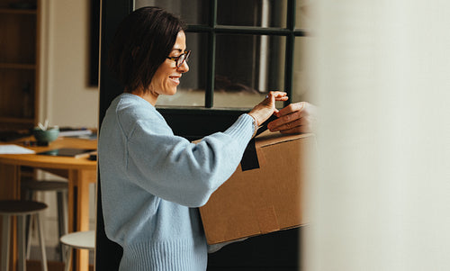 Woman accepts a delivery box from a courier at home