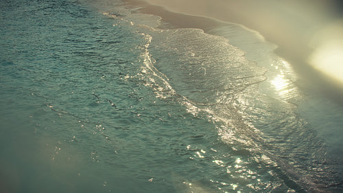 Golden light on gentle ocean wave along pristine beach