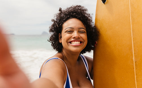 Happy taking a selfie with her surfboard, celebrating summer at the beach